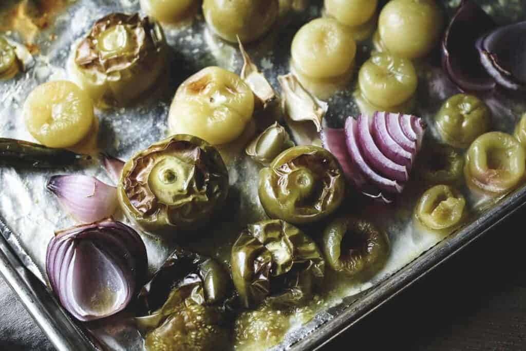 A sheet pan of roasted tomatillos, garlic, onions, and peppers.