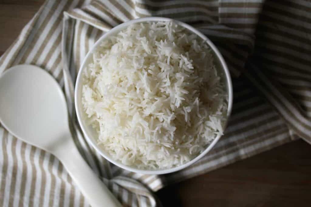 White rice in a white bowl on a striped towel