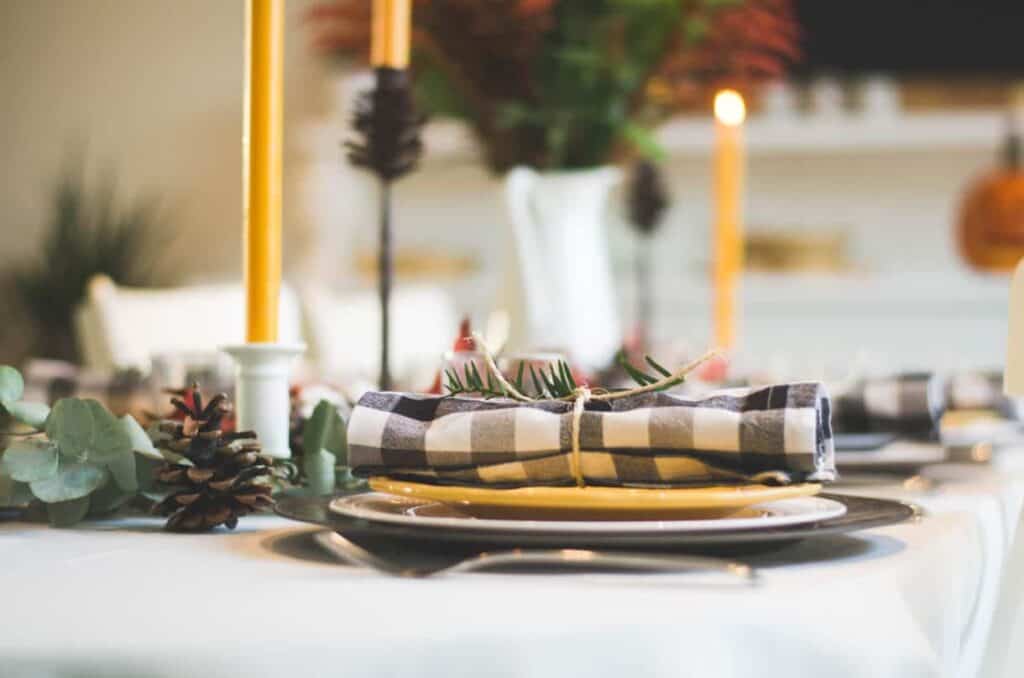 Photo by Libby Penner on Unsplash. Black and yellow holiday tablescape with Jack-o-lantern.