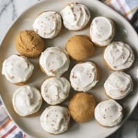 frosted pumpkin cookies on a cream plate