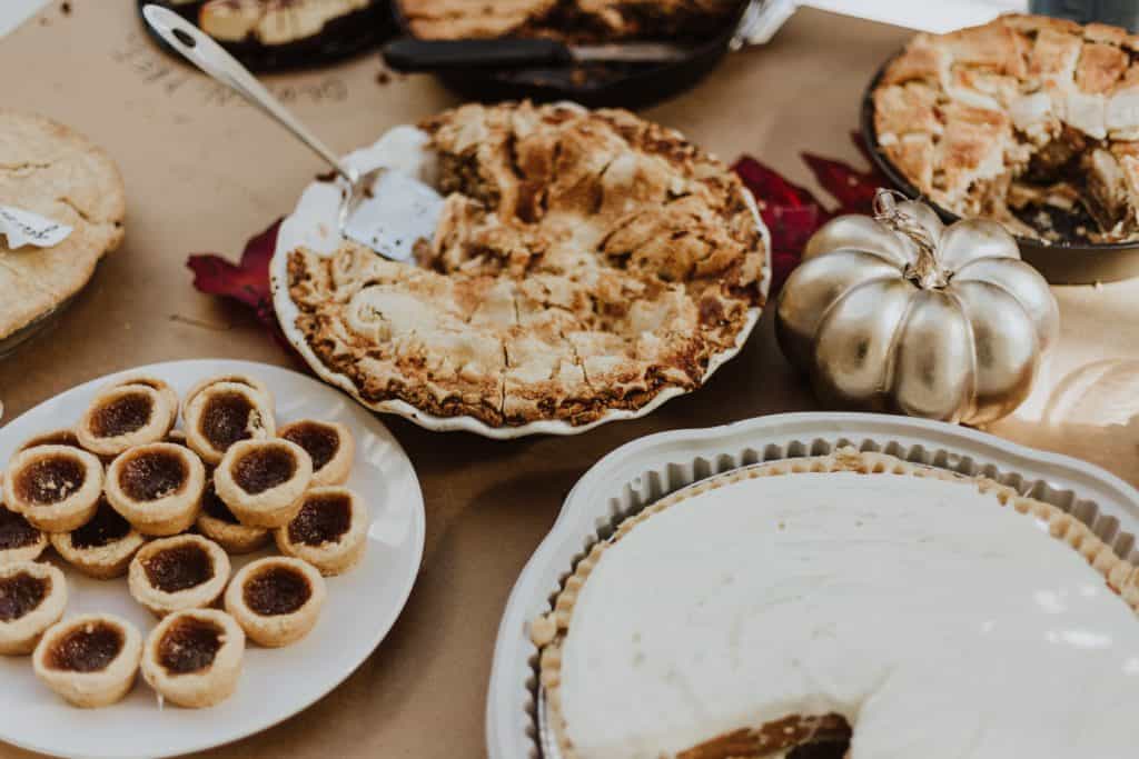 A buffet of pies and cookies, some gluten free, a silver pumpkin.