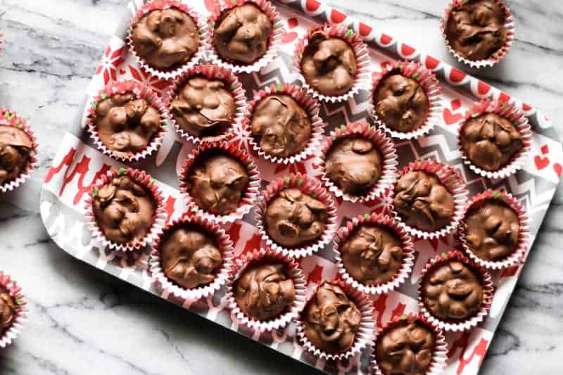 a red and gray Christmas tray filled with clusters of crockpot candy