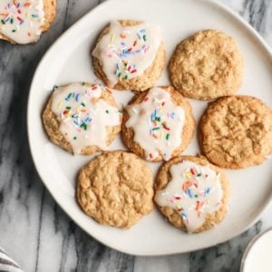 iced oatmeal cookies with rainbow sprinkles on a round cream plate