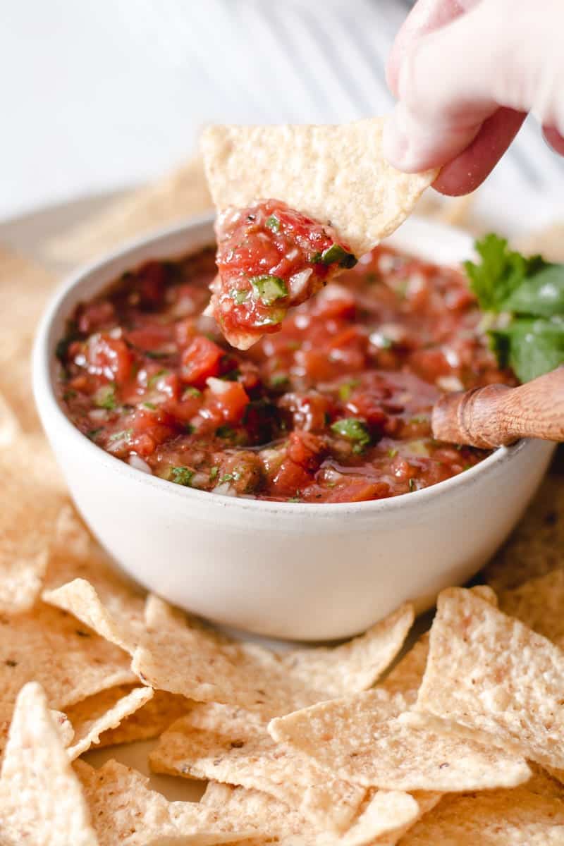 Dipping a tortilla chip into a bowl of salsa.