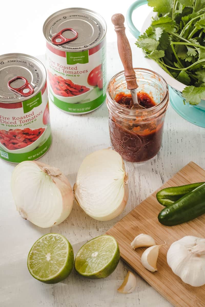 Ingredients for easy salsa: canned tomatoes, lime, chipotles, onion, garlic, and cilantro.