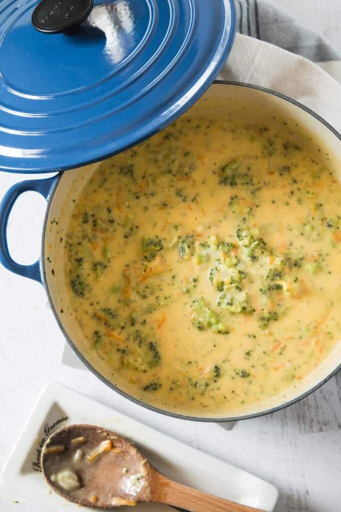 A big blue Le Crueset pot filled with broccoli cheddar soup.