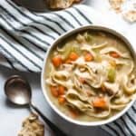 a bowl of chicken noodle soup with a soup spoon.
