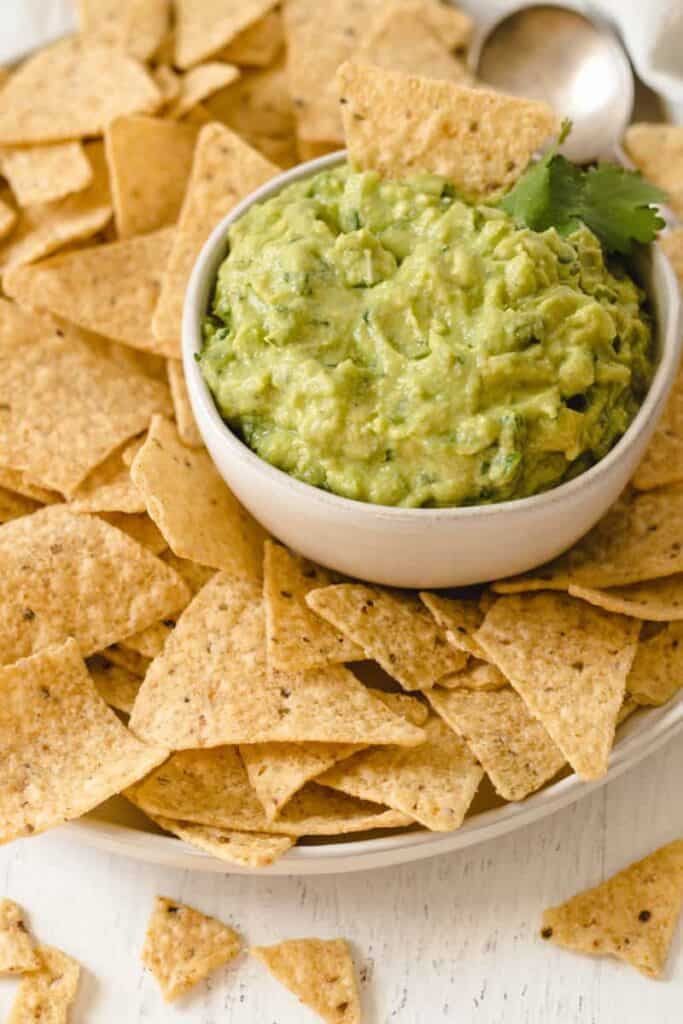 Easy to make guacamole in a bowl surrounded by tortilla chips.