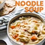 A bowl of chicken noodle soup with crackers.