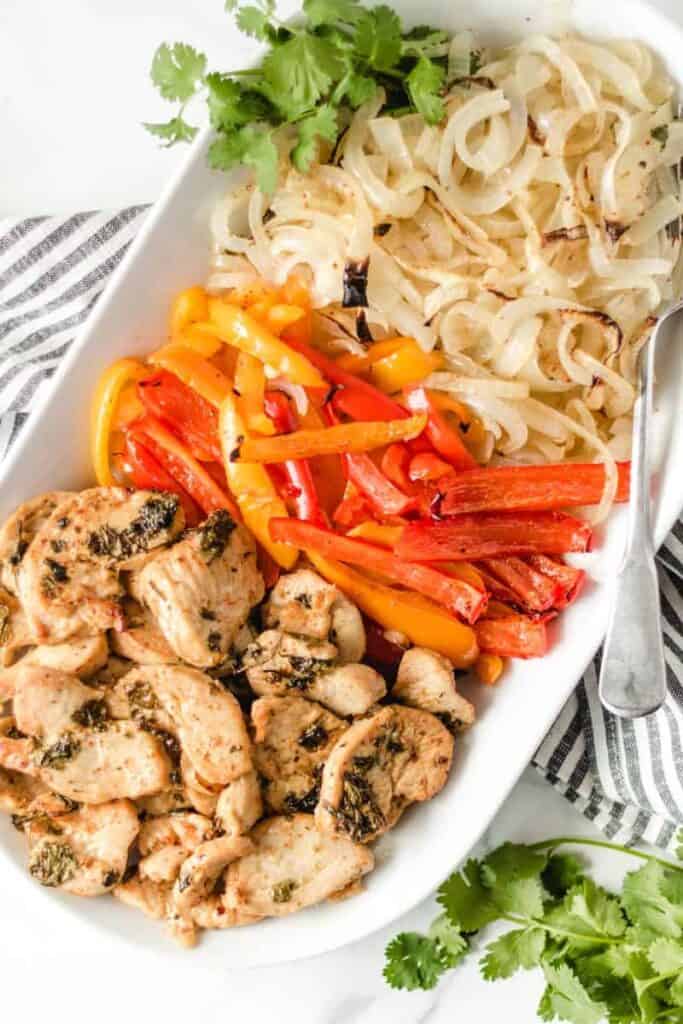 Cooked chicken fajitas on a white serving platter.
