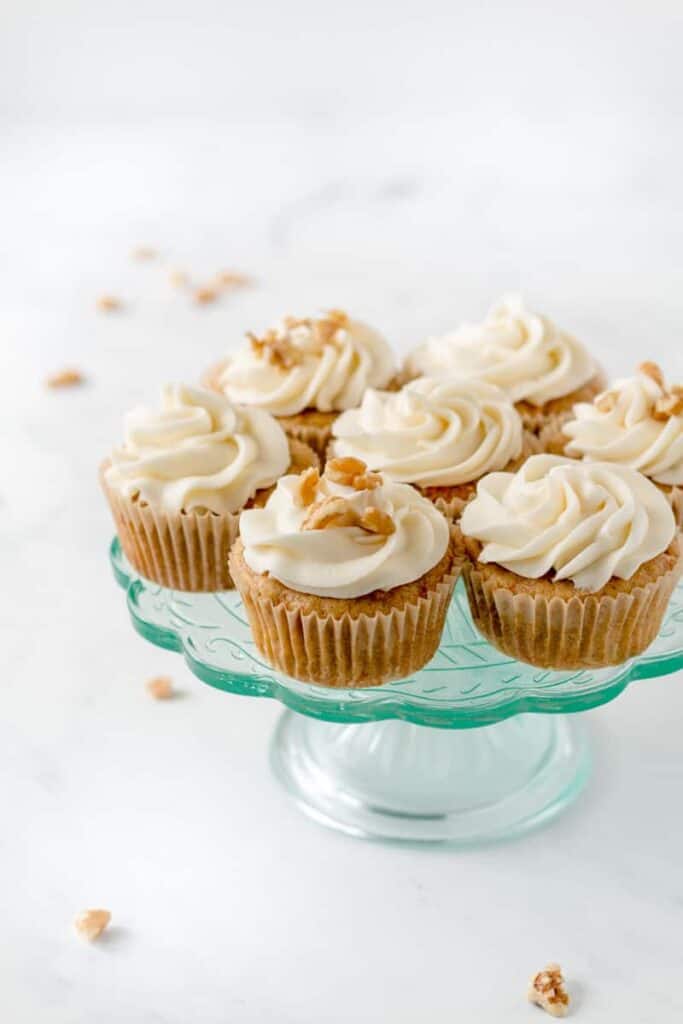 Carrot cake cupcakes with cream cheese frosting on an aqua cake stand.
