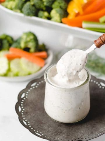 A spoon dipping into a jar of homemade ranch dip.