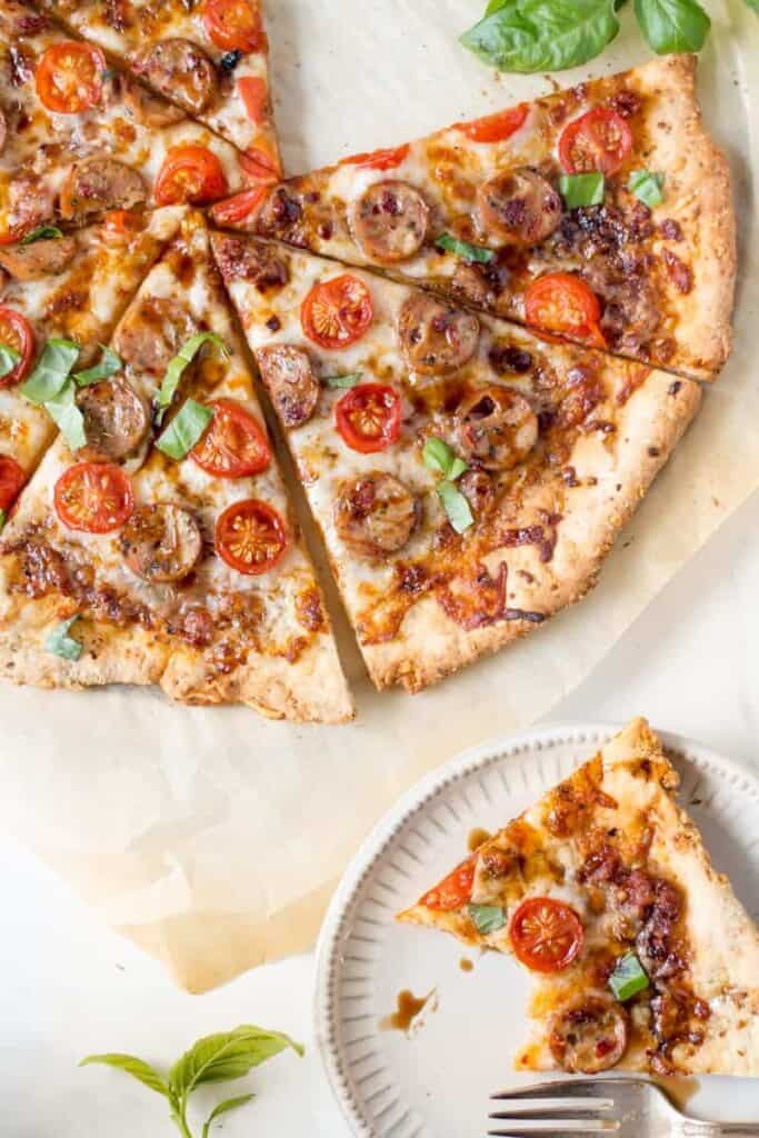 A caprese chicken pizza with a slice on a plate, half eaten.