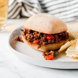 Sloppy Joe sandwich in front of blue pot and striped towel.