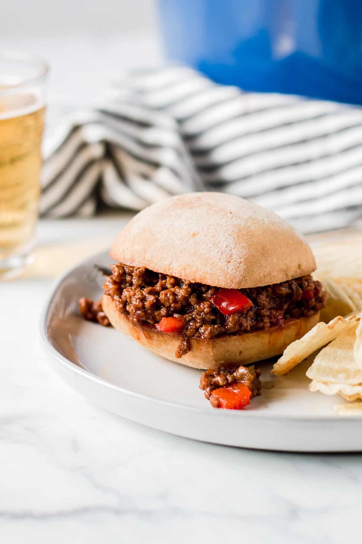 Sloppy Joe sandwich in front of blue pot and striped towel.