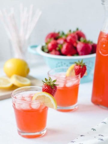 Two glasses of homemade strawberry lemonade with lemon and strawberry garnish.