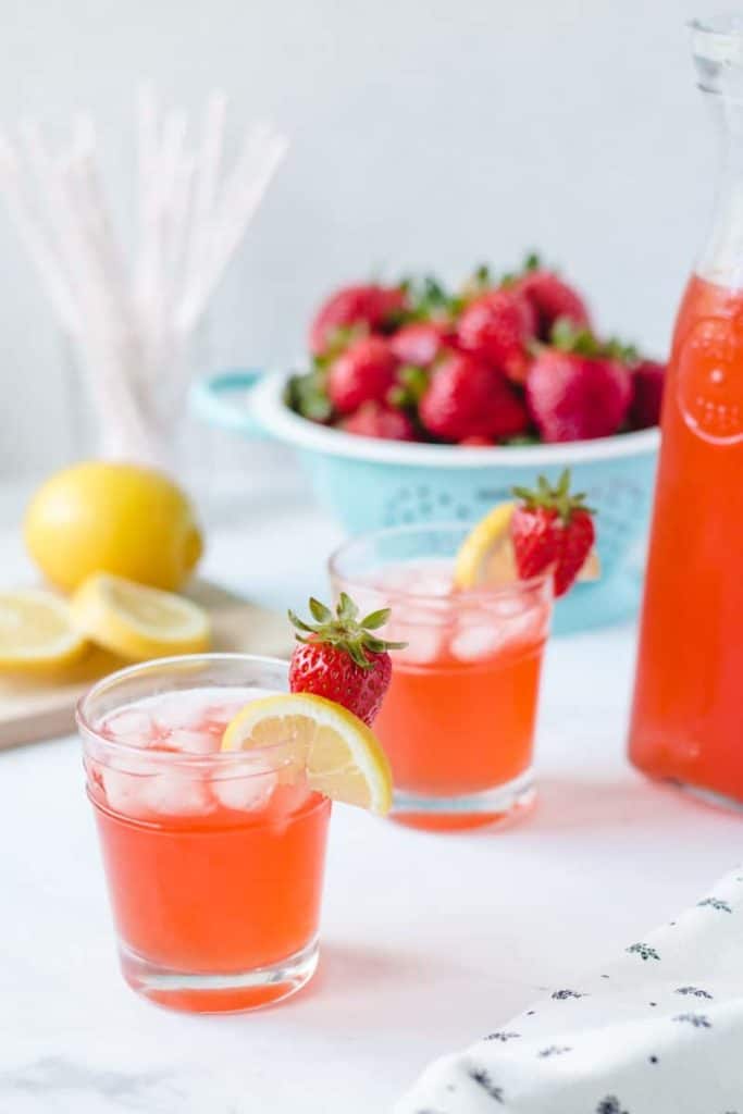Two glasses of homemade strawberry lemonade with lemon and strawberry garnish.