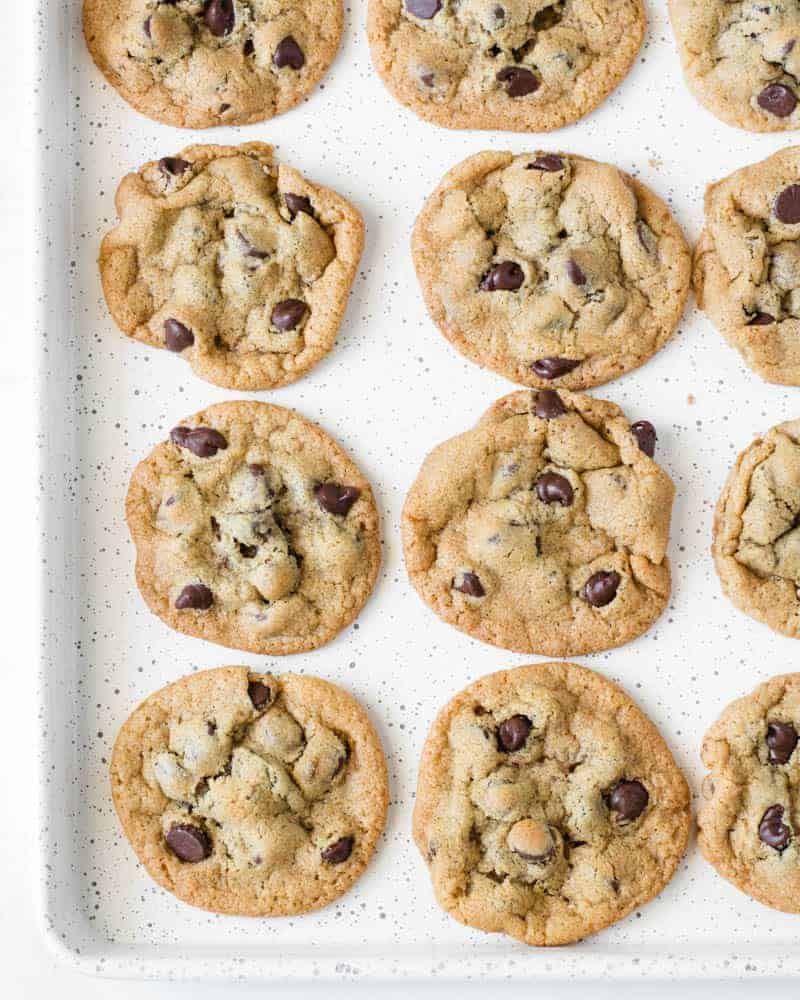 A speckled cookie sheet with baked chocolate chip cookies on it.