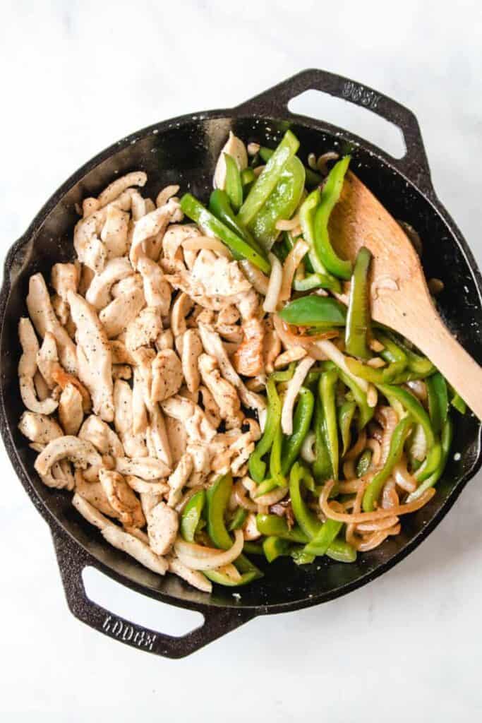 Lodge dual handle, cast-iron pan with sautéd chicken strips, onions, and bell pepper.