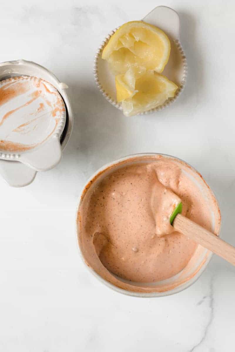 Empty ingredient dishes next to a small bowl of chipotle aioli and a spent lemon wedge.