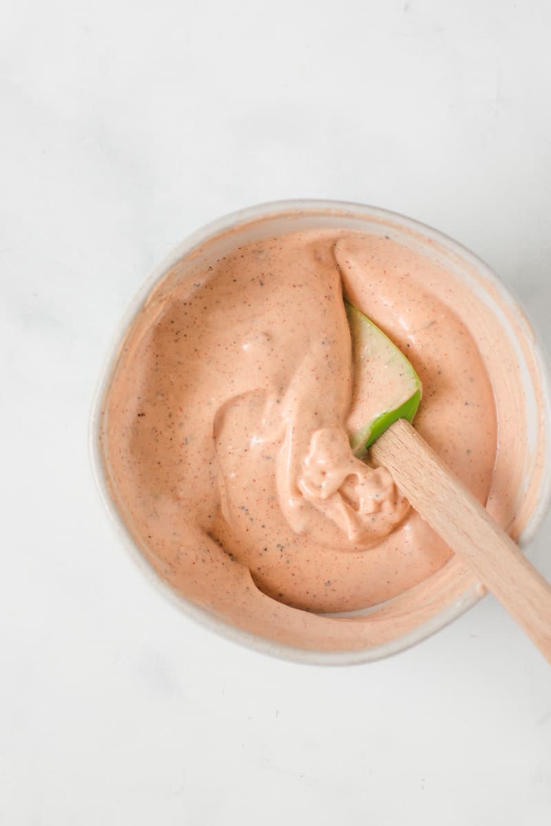 Stirring up the mayo in a small bowl with a green spatula.