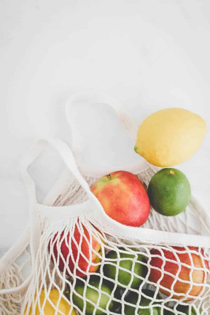 Ikea KUNGSFORS mesh produce bag with apples, lemons, and limes spilling out.