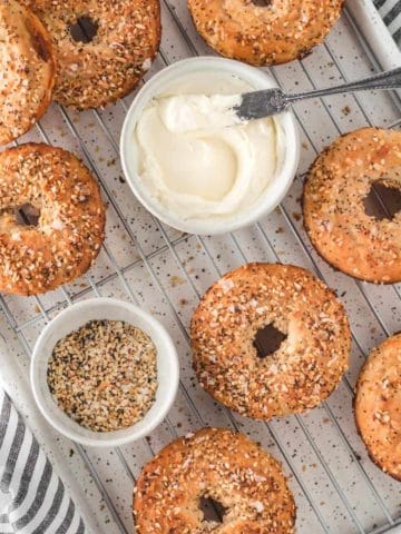 Two-Ingredient gluten free bagels on a cooling rack with cream cheese and everything bagel seasoning.