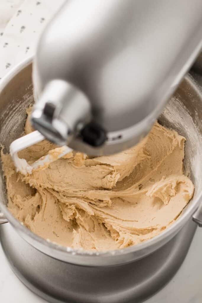 Creamed and blended cookie dough in bowl of a stand mixer.