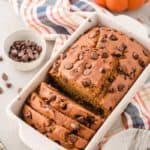 Gluten-free Chocolate Chip Pumpkin Bread, partially sliced, in white loaf pan.