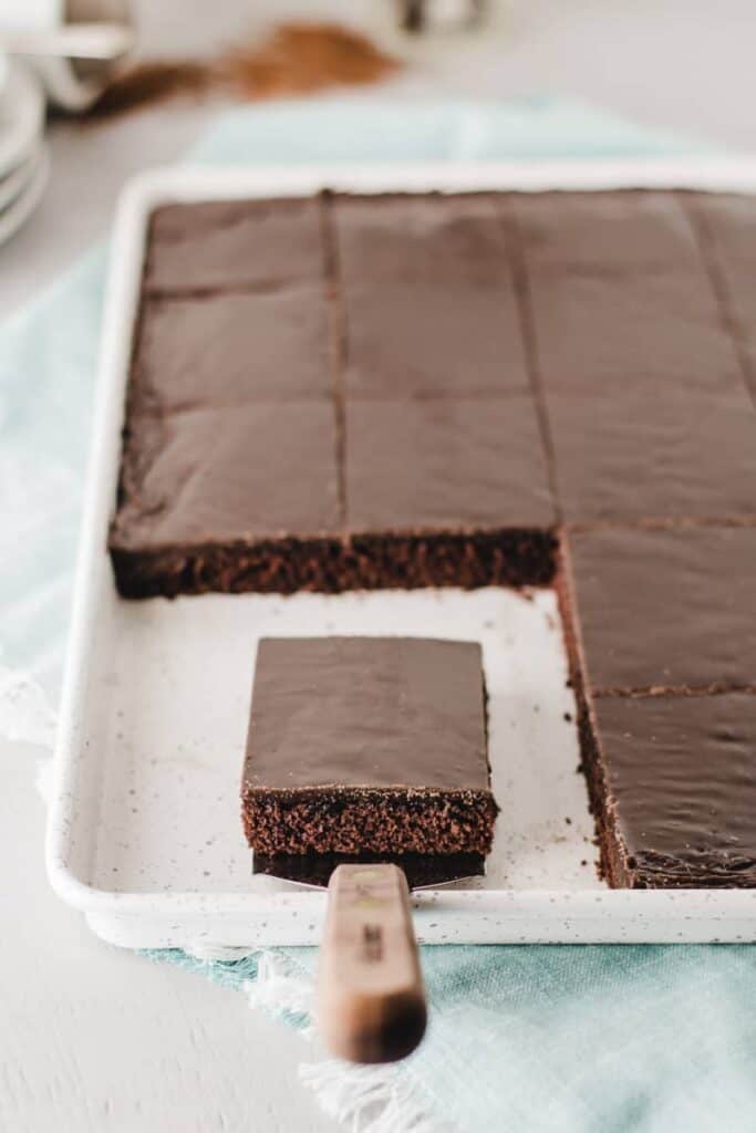 Gluten-free Texas Sheet Cake, sliced in pan.  One slice on serving spatula.