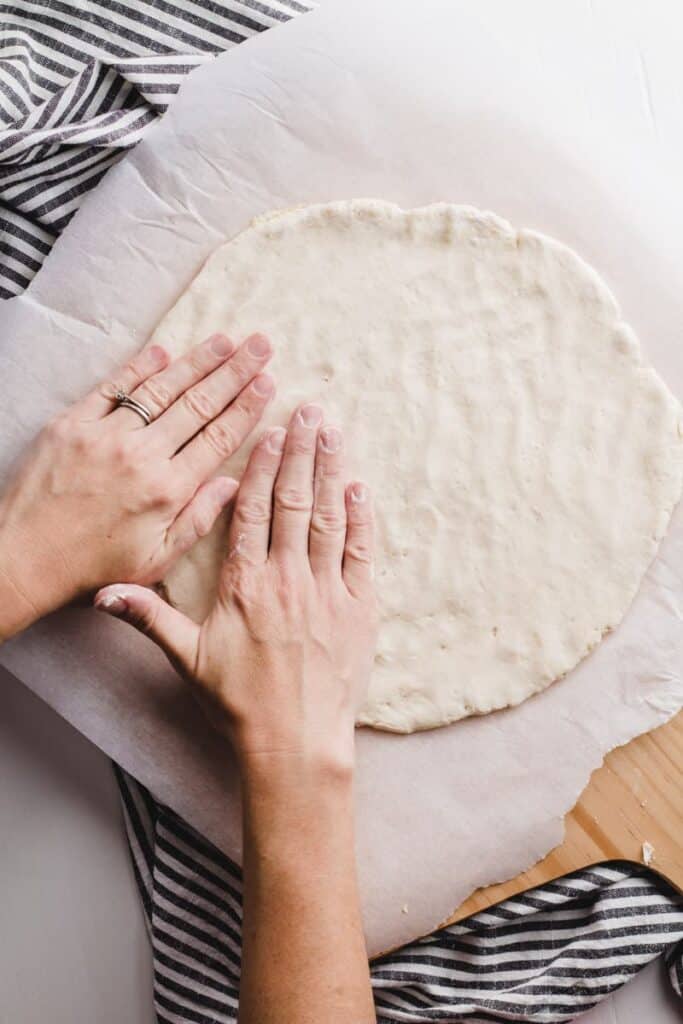 Patting out the pizza dough with rice flour