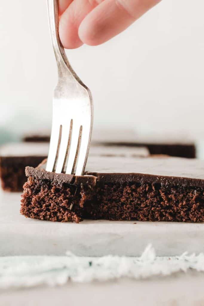 A fork sunk into corner of a slice of Texas sheet cake.