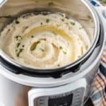 A white instant pot full of mashed potatoes with butter and parsley on top.