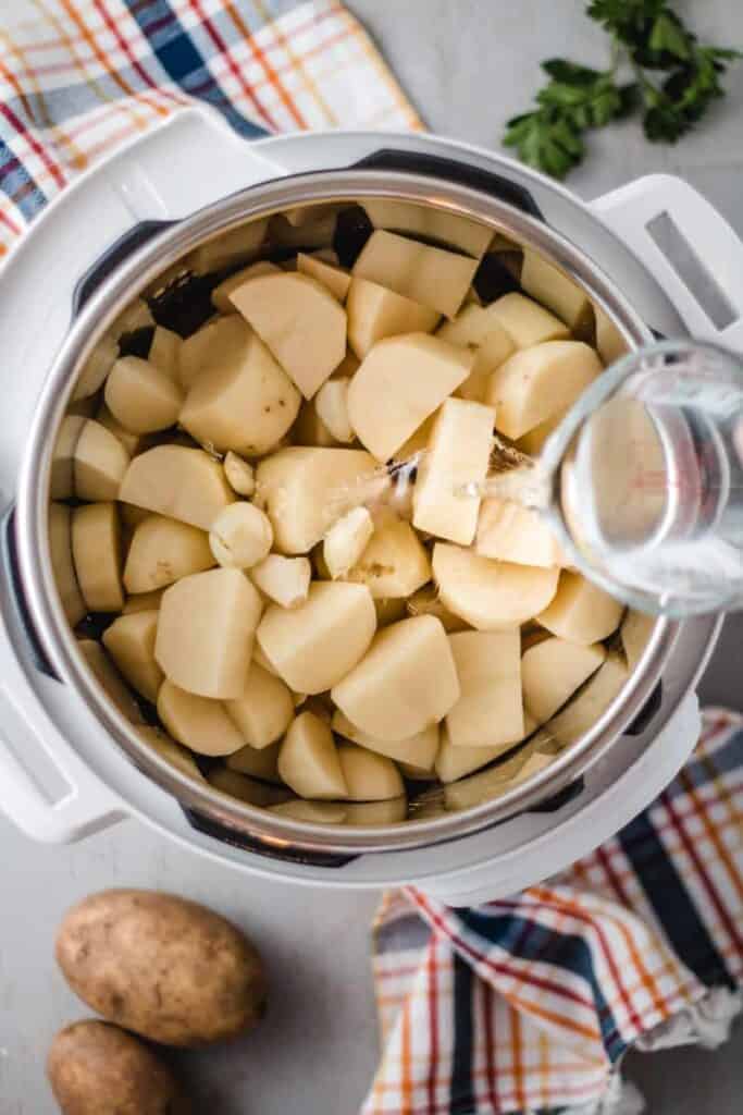 Pouring water over diced potatoes in the instant pot.