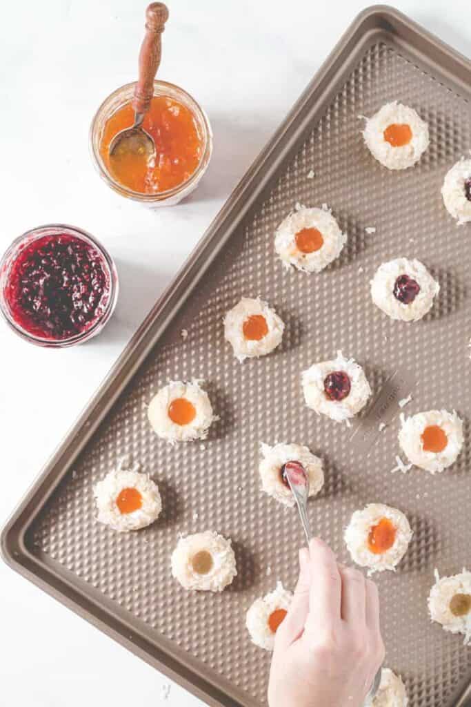 Filling unbaked thumbprints with raspberry and apricot jam.