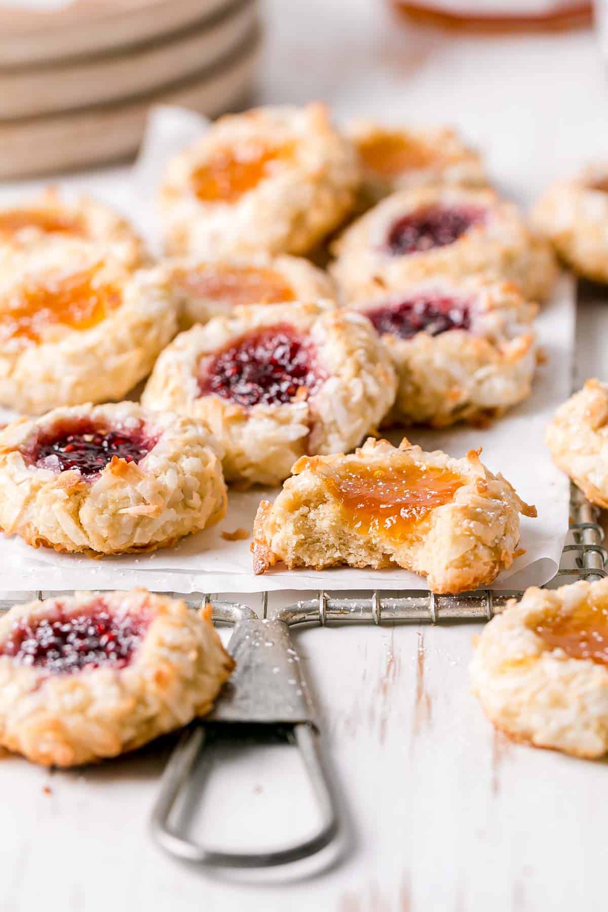 Gluten free thumbprints filled with apricot and raspberry jam on a wire rack.