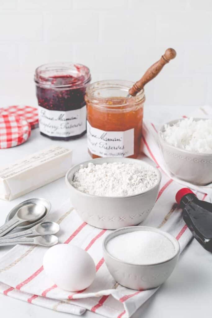 Ingredients for gluten-free thumbprints portioned out, Bonne Maman Jam in the background.