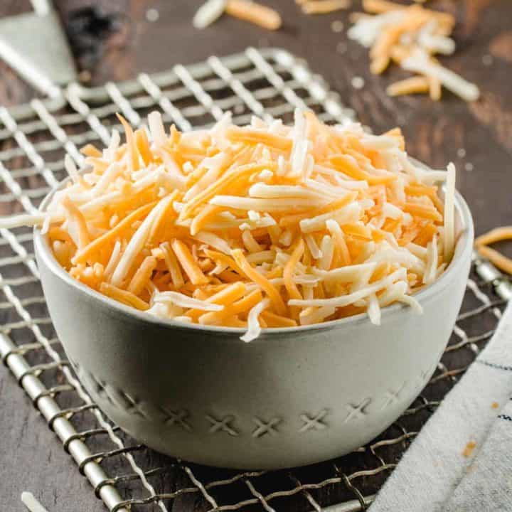 A bowl of shredded cheese on a vintage cheese grater.