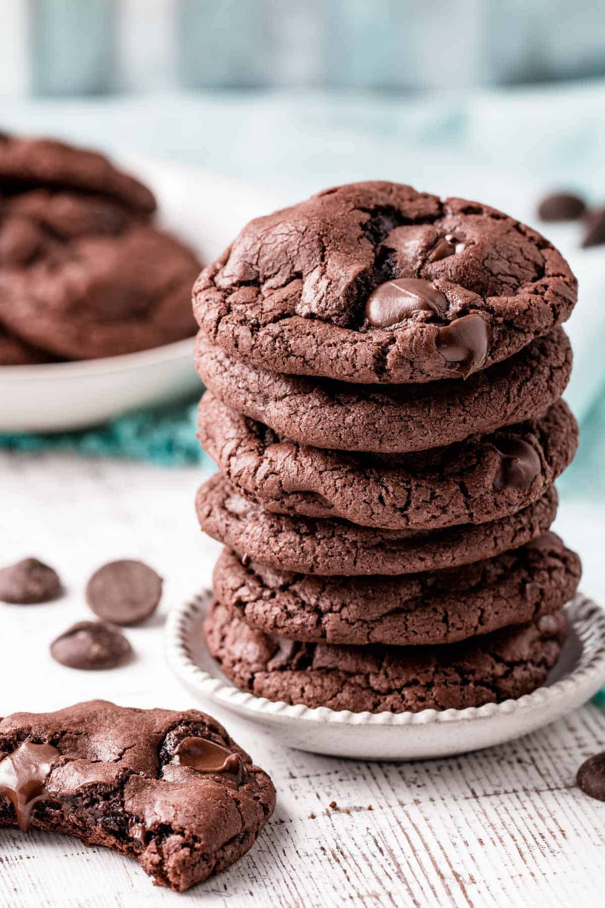 A stack of chocolate cookies with a half eaten cookie next to it.