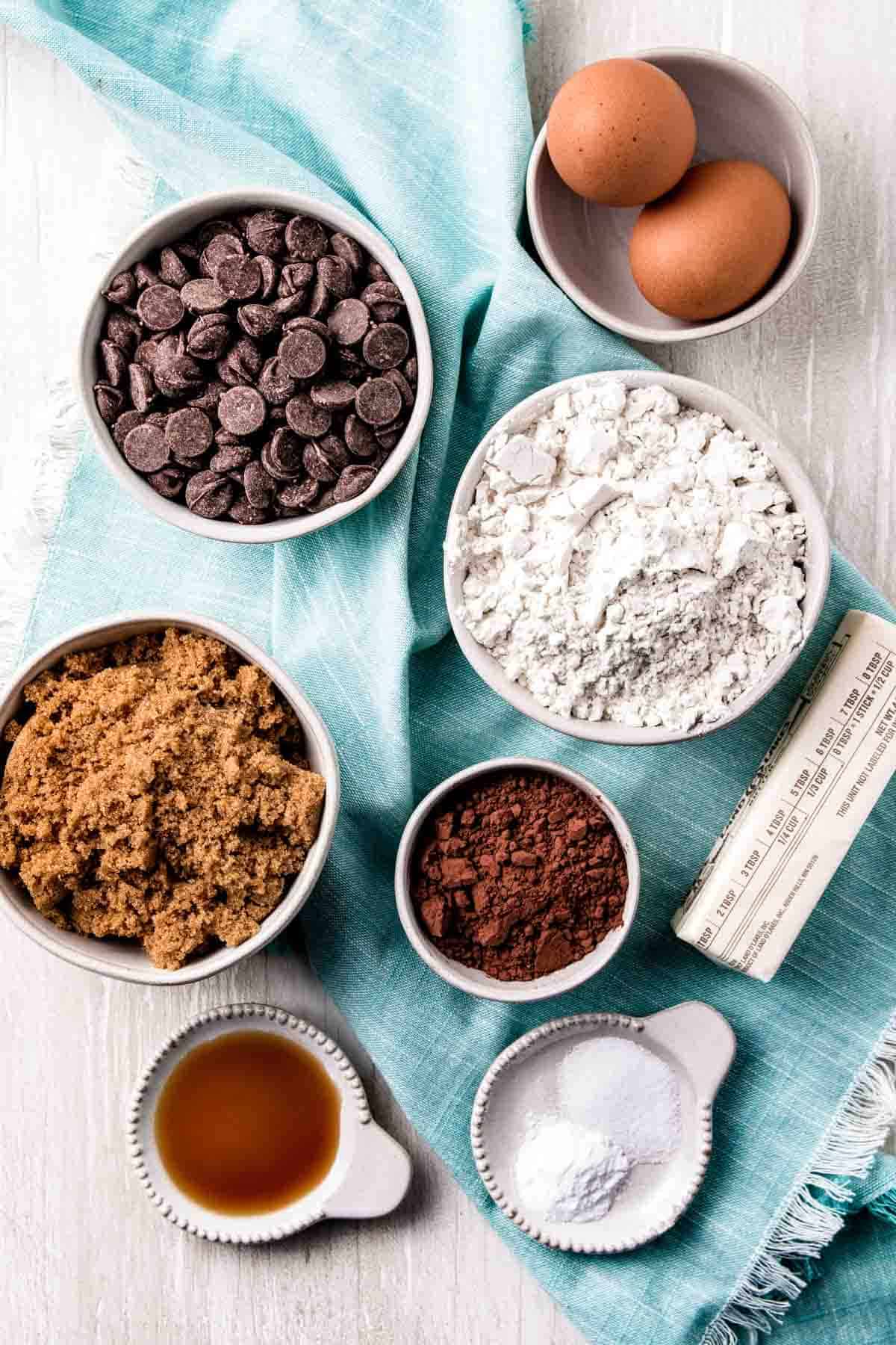 Ingredients in gluten-free double chocolate chip cookies measured out in bowls on a teal napkin.