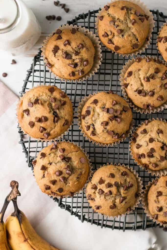 Muffins studded with chocolate chips on a black wire rack.