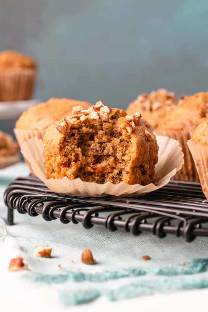 A gluten-free carrot muffin with a bite removed to show inside texture.