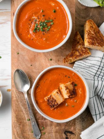 Gluten-free tomato soup in bowls with chives and grilled cheese.