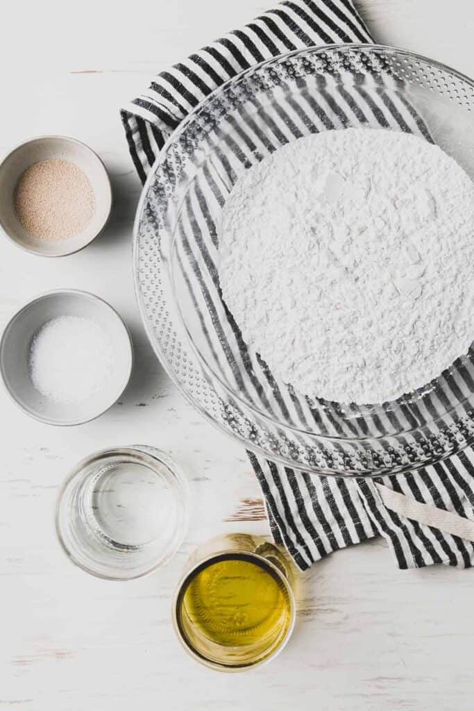 Ingredients for the pizza dough: Fioreglut flour, yeast, salt, water, and oil all in separate bowls.