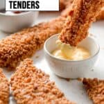 A golden chicken tender is dunked into honey mustard sauce.