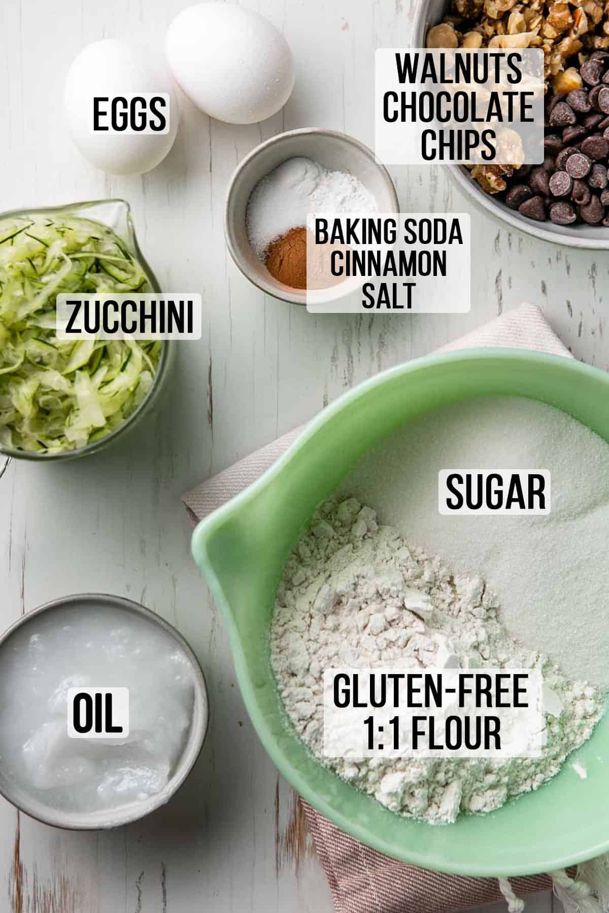 Gluten free flour, sugar, shredded zucchini, oil and remaining ingredients measured out in bowls.