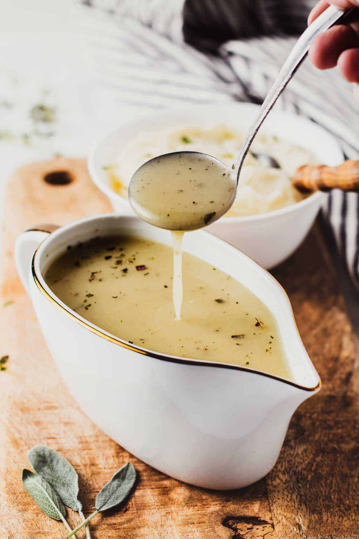 Gluten-free gravy in a gravy boat dripping from a spoon above.