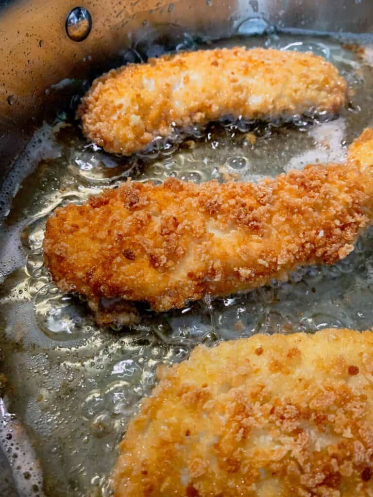 Gluten-free chicken tenders frying in oil.