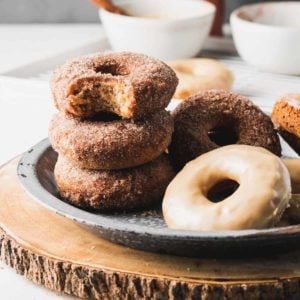 A stack of apple cider donuts, one with a bite taken.