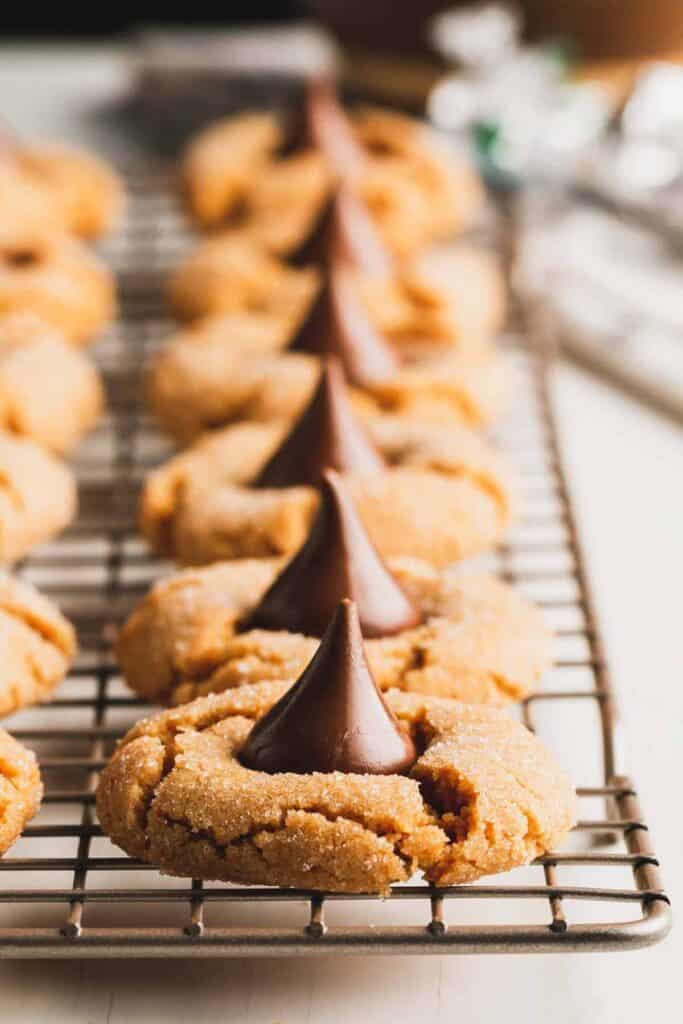 A row of flourless peanut butter blossoms on a wire cookie rack.